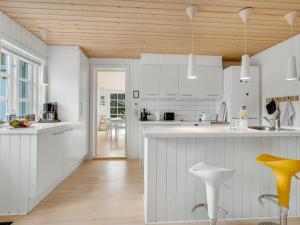 een keuken met witte kasten en een houten plafond bij Holiday Home Toska - 3km from the sea by Interhome in Blokhus