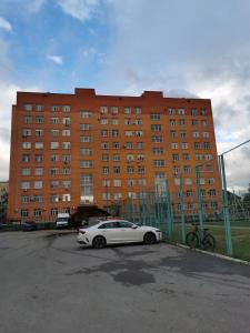 une voiture blanche garée dans un parking en face d'un bâtiment dans l'établissement 2х комнатная студия в центре, новый дом, à Kostanay