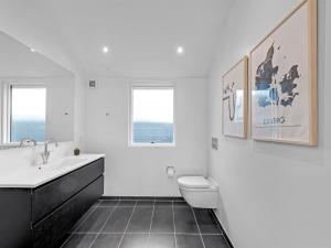 a bathroom with a sink and a toilet and two windows at Holiday Home Carlie - 250m to the fjord by Interhome in Esbjerg
