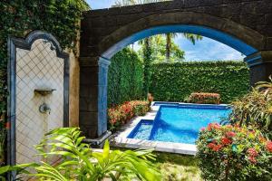 an archway over a swimming pool in a garden at Sunset & Oceanview Terrace, Pool, Beach And Grill in Tamarindo