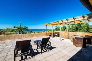 a patio with a table and chairs and the ocean at Sunset & Oceanview Terrace, Pool, Beach And Grill in Tamarindo