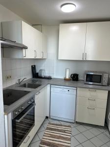 a kitchen with white cabinets and a sink and a microwave at Airport Apartments Rüsselsheim in Rüsselsheim