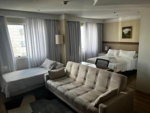 pokój hotelowy z kanapą i łóżkiem w obiekcie Quartos de hotel em frente ao Shopping Vila Olimpia w São Paulo