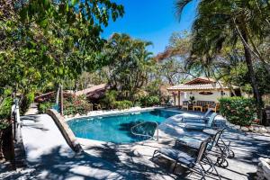 a swimming pool with chairs and a house at Hidden Oasis Across The Street From The Beach in Tamarindo