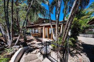 a house surrounded by palm trees and a fence at Hidden Oasis Across The Street From The Beach in Tamarindo