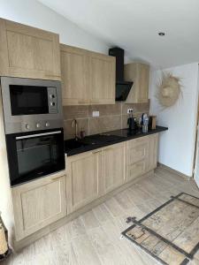 a kitchen with wooden cabinets and a microwave at Spa Sola in Mecquignies