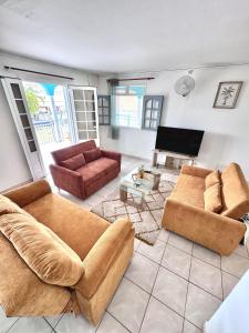 a living room with two couches and a television at Ameli'ber in Sainte-Rose