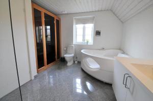 a bathroom with a tub and a toilet and a sink at 10849-Ulfborg-Dommersovej-17 in Øby