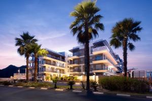 a building with palm trees in front of a street at Yalarent Amazing apartments U360 Complex Eilat in Eilat +20 photos