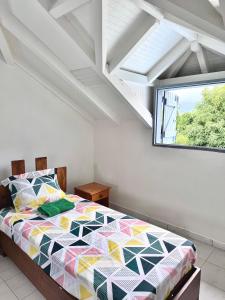 a bedroom with a colorful bed with a window at Ameli'ber in Sainte-Rose