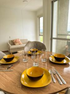 a wooden table with yellow plates and glasses on it at Apartamento con vista al valle cerca al CC llanogrande y el aeropuerto in Palmira
