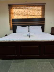 een groot bed met een houten hoofdeinde en witte lakens bij Potomac Hotel managed by Milord hospitality in Ikorodu +2 foto's