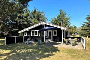 una casa con sedie e ombrellone in cortile di 40893-Ulfborg-Skindbjergvej-393 a Fjand Gårde