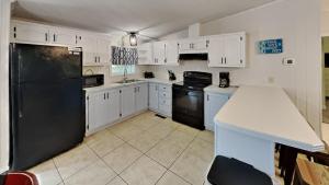 a kitchen with white cabinets and a black refrigerator at Put-in-Bay Island Club #97 in Put-in-Bay
