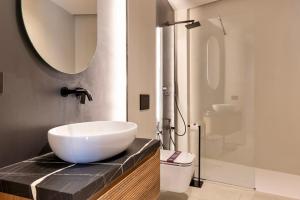 Un baño con lavabo blanco y ducha. en Luxurious 1BR AZULIS holiday Suite#1 in historical centre Olbia, en Olbia
