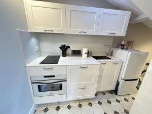 a small kitchen with white cabinets and a refrigerator at Casona del Sol El Retorno - Atico in Lastres