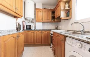 a kitchen with wooden cabinets and a white dishwasher at Amazing Apartment In Altea With Kitchen in Altea