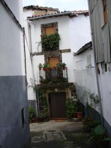 an alley with a white building with plants on it at Apartamentos Rurales La Lancha in Aldeanueva de la Vera