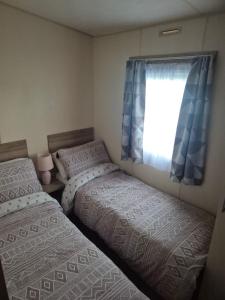 two beds in a small bedroom with a window at Gosling Retreat in Cayton
