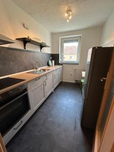 a kitchen with white cabinets and a black refrigerator at Monteurwohnung I Wi-Fi I Nähe Boxberg & Schwarze Pumpe in Burgneudorf