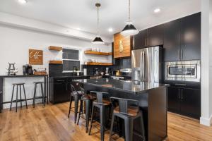 a kitchen with black cabinets and a bar with stools at Pineapple Shores - Stay for 14 in Hollister