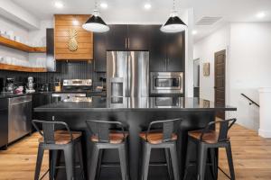 a kitchen with a large black counter with three bar stools at Pineapple Shores - Stay for 14 in Hollister