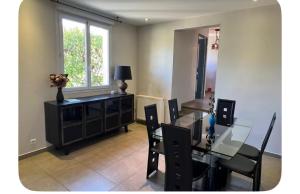 a dining room with a table and chairs and a window at Villa familiale piscine proche de Paris in Antony