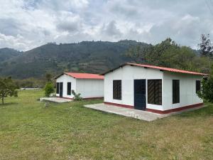 two white buildings in a field with mountains in the background at Finca Turística El Porvenir in Cáqueza