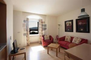 una sala de estar con 2 sofás rojos y una ventana en Casa de los Beneficiados, en Roncesvalles