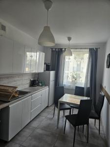 a kitchen with white cabinets and a table and chairs at 5 min od Dworca PKP Apartament in Lublin +16 photos