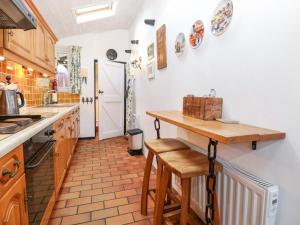 een keuken met een aanrecht en een tafel met krukken bij Hollyhedge Cottage in Briston