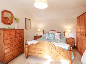 een slaapkamer met een houten bed en een houten dressoir bij Hollyhedge Cottage in Briston