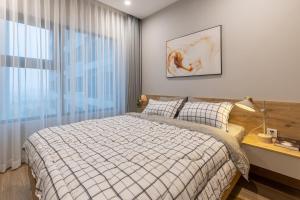 a bedroom with a bed and a large window at StayLocal Apartment in Long Bình