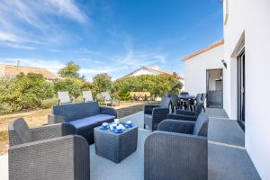 a patio with couches and a table and chairs at La Maison du Payré - 2 personnes in Talmont