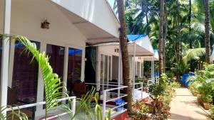 a white house with palm trees in front of it at CSF Boutique Homestay in Palolem