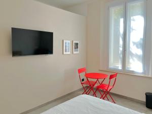 モデナにあるRed Collection, Boutiques Rooms & Suites, Modena City Centerの赤い椅子2脚、テーブル、テレビが備わる客室です。