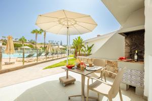 un tavolo e sedie con un ombrellone in un patio di Vista Verde - Adults Only a Maspalomas