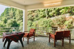 a porch with a table and chairs and a view at Vista Hills by Bala's in Mussoorie
