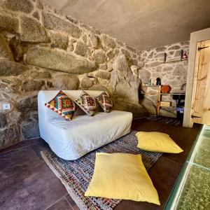 a living room with a white couch in a stone wall at Gardunha Stone in Louriçal do Campo