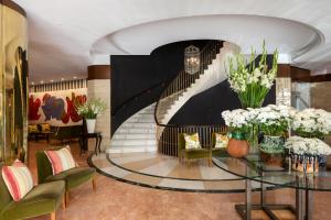 a lobby with a staircase with vases of flowers on a glass table at RL Ciudad de Úbeda in Úbeda
