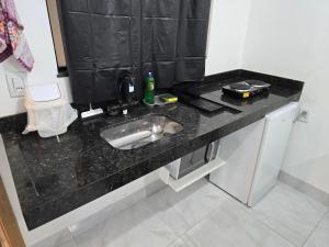 een zwart aanrecht met een wastafel in een kamer bij Flat completo 14 minutos do centro do Buriti Shopping in Aparecida de Goiania +24 foto's