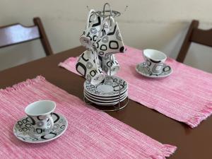 a table with two cups and a vase on a table at Apto com Sacada e Wi-Fi – 5 min da Praia! in Samaritá