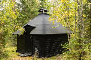 a black outhouse with a black roof in the woods at Northern Lights Kota Stay By BookLapland in Rovaniemi