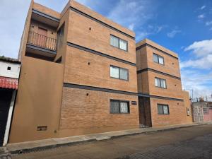 a brown brick building with a balcony on a street at Kooch Aparthotel in Oaxaca City