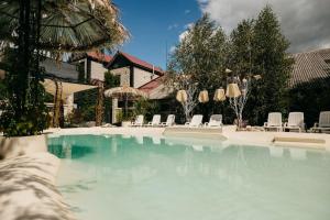 a swimming pool with white chairs and umbrellas at loft apartments OLD MILL in Sarny