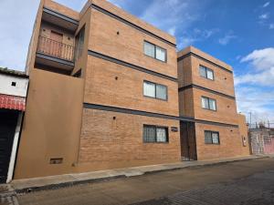 a brown brick building with a balcony on a street at Kooch Aparthotel in Oaxaca City +71 photos