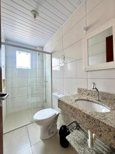 a bathroom with a toilet and a sink and a shower at Pousada Massiambu in Palhoça