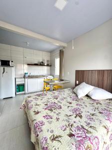 a bedroom with a large bed and a kitchen at Pousada Massiambu in Palhoça