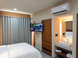 a bedroom with a bed and a sink and a television at Kooch Aparthotel in Oaxaca City