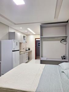 ein Schlafzimmer mit einem weißen Bett und einem Kühlschrank in der Unterkunft Studio 14 - 2K Atalaia Apenas 150m da Orla in Aracaju